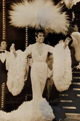 une photo en noir et blanc d'une femme portant une robe et un chapeau à plumes