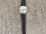 wrist watch with black leather strap and white dial on a cow skin surface