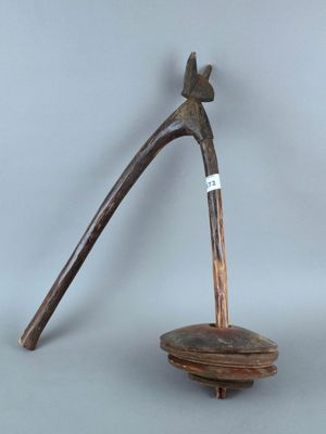 un petit objet en bois muni d'un manche en bois et posé sur un socle