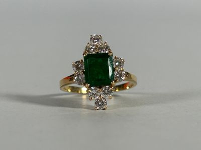 a close up of a ring with a green stone surrounded by diamonds