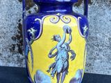 a blue and yellow vase sitting on a black surface