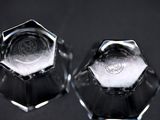 pair of clear glass candlesticks with a crest on each of them