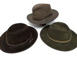 trois chapeaux sont alignés sur une surface blanche