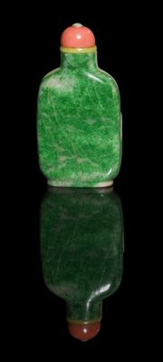 green jade snuff bottle with a red cap on a black surface