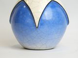 a blue and white vase with a white top on a white surface