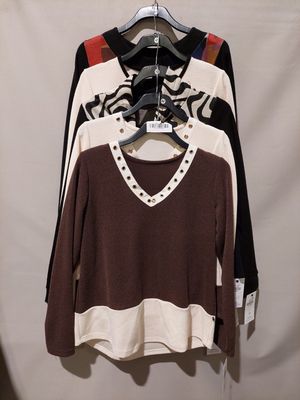 three sweaters hanging on a hanger in front of a white wall