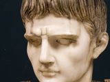 marble bust of a man wearing a brown vest and a brown shirt