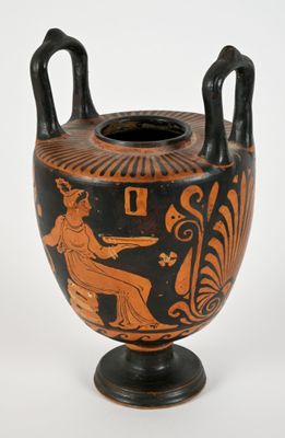 a black and orange vase on a stand on a white surface