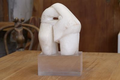 une statue représentant deux personnes se tenant la main, posée sur une table en bois