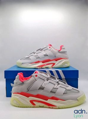 une paire de baskets grises et roses posée sur une boîte bleue
