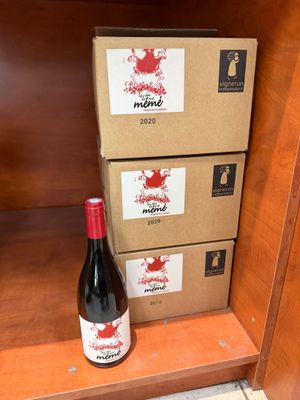 une bouteille de vin posée sur une étagère à côté de cartons de vin