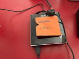 un ordinateur portable posé sur une table, avec un bout de papier accroché dessus