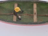 a small green boat with a yellow top on a white surface