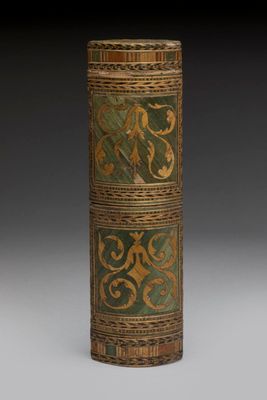an old wooden cylinder with a green and gold design on it