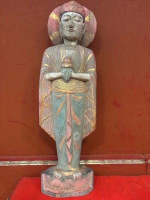 une vieille statue d'un homme avec un chapeau sur une plate-forme rouge
