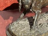 une statue en bronze représentant un chien et un chat posée sur une table
