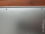 the back of a silver laptop computer sitting on top of a wooden table