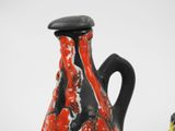 a red and black vase sitting next to a black and white vase