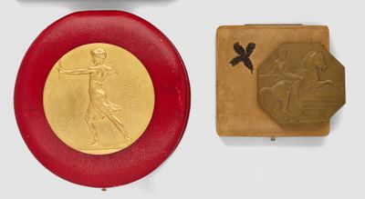 two gold medals and a red plaque on a white surface