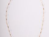 un collier à chaîne en or composé d'un long maillon et d'une petite perle