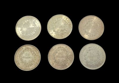 six different types of silver coins on a black background