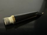 a black pen with a gold tip on a black table