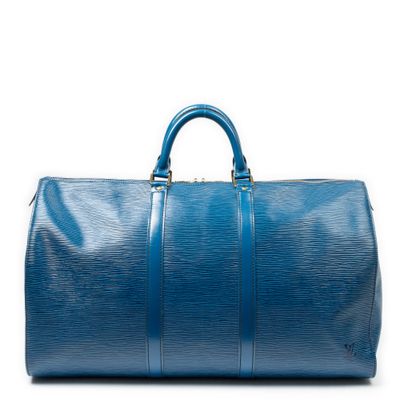 un sac de voyage bleu posé sur une surface blanche
