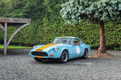 a blue and orange sports car parked in front of a tree