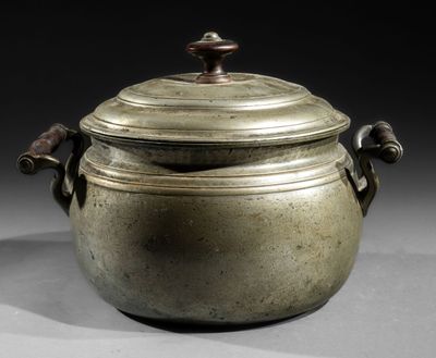 an old metal pot with a lid and handles on a table