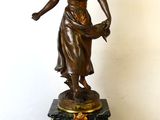 une statue de femme tenant une horloge sur une table