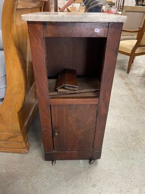 un petit meuble en bois avec un plateau en marbre, monté sur roulettes