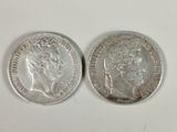 two silver coins sitting side by side on a white surface