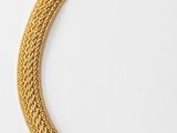 a gold necklace with a chain that has been set on a white surface