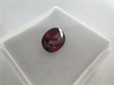 a close up of a red garnet stone on a white surface