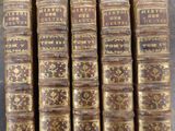 six old books are stacked on top of each other on a table