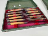 six knives in a green case on a white table