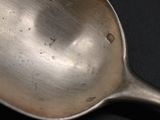 a silver spoon with a hole in it on a black surface