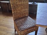 une chaise en osier placée à côté d'une table dans un salon