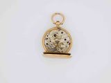 a close up of a small gold pocket watch on a white surface