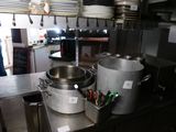 des casseroles et des poêles sont posées sur un plan de travail dans une cuisine professionnelle