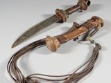 une paire de couteaux en bois et en métal, attachés par une corde, posés sur une surface blanche