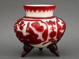 a red and white vase sitting on top of a table