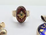 three rings and a pendant are sitting on a white surface