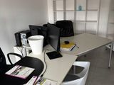 un bureau avec un ordinateur et plusieurs chaises dans la pièce
