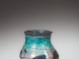 a glass vase with a painting on it sitting on a table