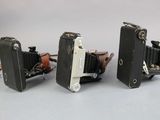three old cameras sitting side by side on a table