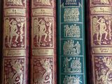 three old books are lined up on a shelf next to each other