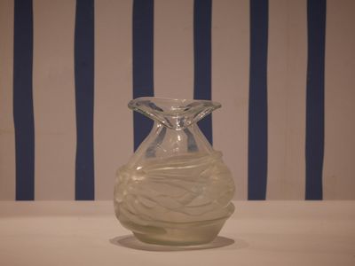 a glass vase sitting on a table in front of a striped wall