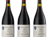 three bottles of red wine sitting next to each other on a white surface
