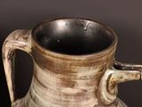 a brown and white vase with a handle on it